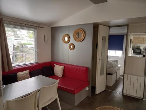 un salon avec un canapé rouge et une table dans l'établissement Mobil Home 2 chambres avec terrasse, à Saint-Hilaire-de-Riez