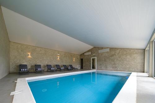 a swimming pool in a room with chairs around it at Sorraia Hotel Rural in Santa Justa