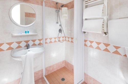 ein Badezimmer mit Dusche, Waschbecken und Spiegel in der Unterkunft Hotel Carnaby in Rimini