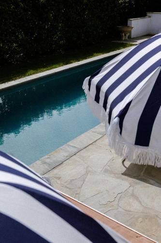 two beach umbrellas sitting next to a swimming pool at VILLA Centre Guethary piscine acces ocean a pied in Guéthary