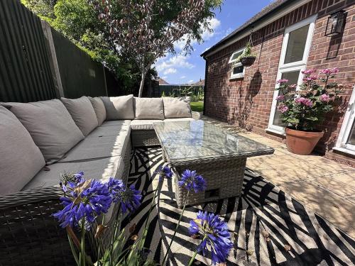 Un patio con un sofá y una mesa y flores moradas. en Light, airy and spacious 3 bed home, en Dorney