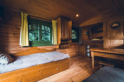 a room with a bed in a wooden cabin at Domaine de La Ville Suzanne - Chambres d'hôtes, Roulottes et Cabanes in Saint-Donan