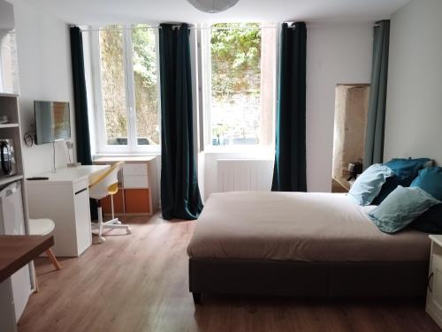 une chambre avec un lit, un bureau et des fenêtres dans l'établissement Studio sur cour, Centre-ville, à Morlaix