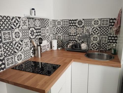 d'une cuisine avec un comptoir, un évier et un mur en carrelage. dans l'établissement Studio sur cour, Centre-ville, à Morlaix