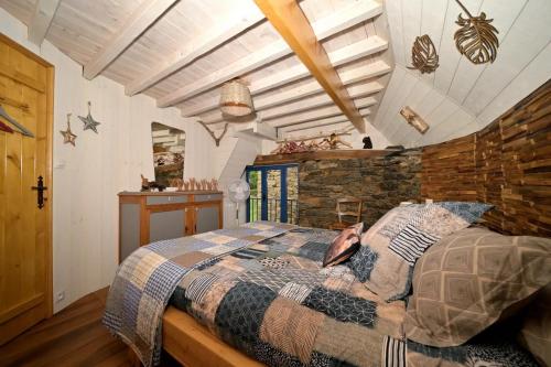 une chambre avec un lit et un mur en pierre dans l'établissement La Grange de l'Ours, à Saint-Lary