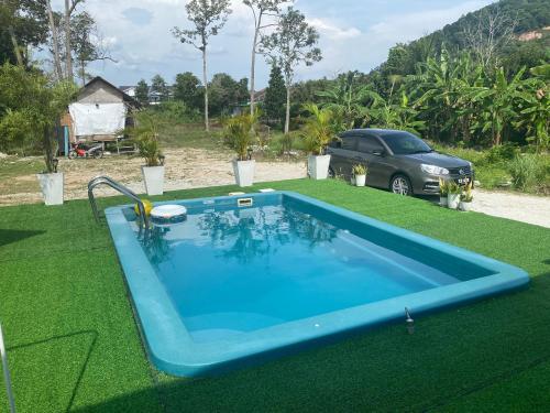 a blue swimming pool on the grass with a car at Maison Helysa Homestay in Lumut