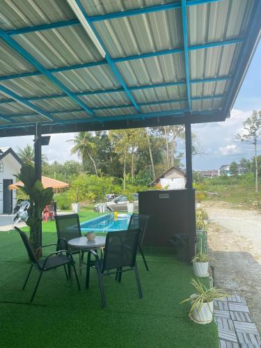 a patio with a table and chairs and a pool at Maison Helysa Homestay in Lumut
