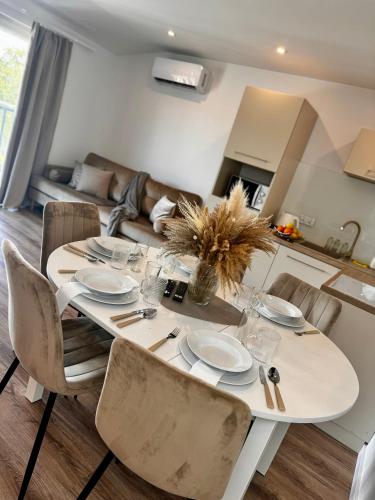 a dining room table with chairs and a white table and chairsktop at Apartamenty Modrzewiowa Zator in Piotrowice