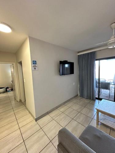 a living room with a couch and a tv on a wall at Tranquility - Banana Beach Club in Port Shepstone