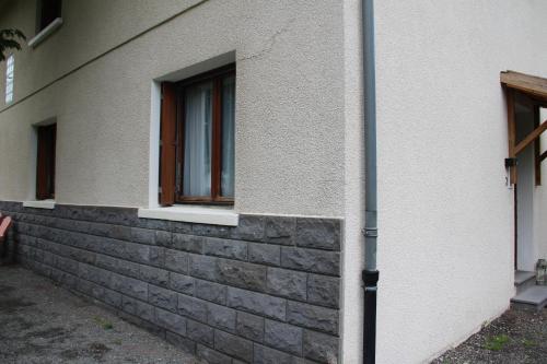 une fenêtre sur un mur en briques à côté d'un bâtiment dans l'établissement Les Cimes 2, à Mont-Dore