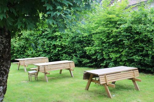 trois tables de pique-nique et bancs dans un parc dans l'établissement Les Cimes 2, à Mont-Dore