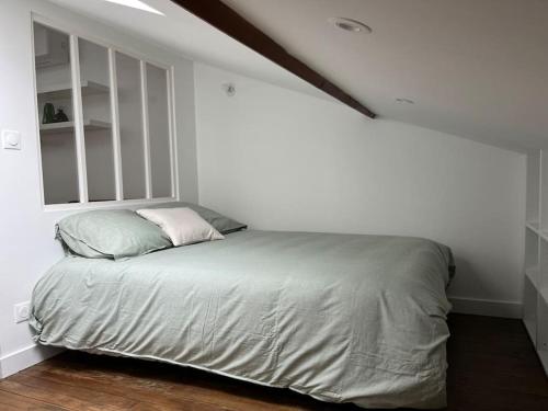 Ce lit se trouve dans une chambre blanche dotée d'une fenêtre. dans l'établissement Appartement refait à neuf à proximité du centre ville, à Toulouse