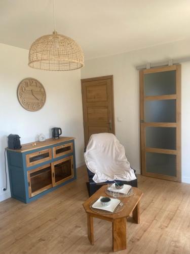 - un salon avec une table et une horloge murale dans l'établissement Logement indépendant au calme avec terrasse, à Mazerolles-le-Salin