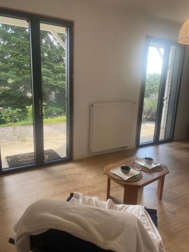 - un salon avec une table et de grandes fenêtres dans l'établissement Logement indépendant au calme avec terrasse, à Mazerolles-le-Salin