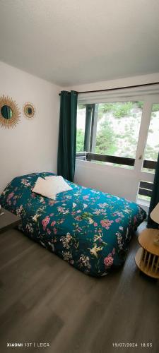 - une chambre avec un lit doté d'une couverture fleurie et d'une fenêtre dans l'établissement Appartement au ski 2 adultes et 2 enfants La Norma, à Villarodin-Bourget