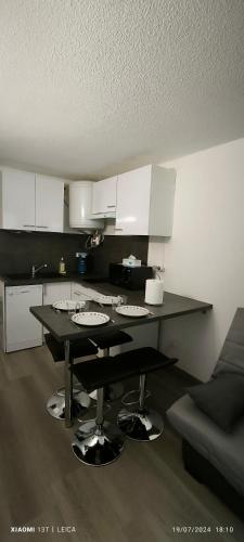 une cuisine avec une table noire et des armoires blanches dans l'établissement Appartement au ski 2 adultes et 2 enfants La Norma, à Villarodin-Bourget