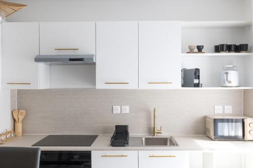 une cuisine blanche avec un évier et un micro-ondes dans l'établissement Lanova appartement pour 6 proche Disneyland Paris, à Chessy