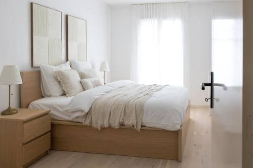 une chambre avec un lit avec des draps blancs et des oreillers dans l'établissement Lanova appartement pour 6 proche Disneyland Paris, à Chessy