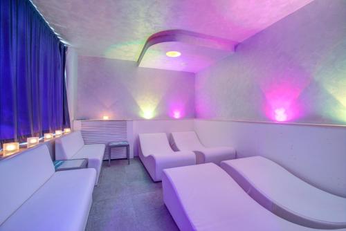 a room with purple lights and white couches at Ferretti Beach Hotel in Rimini