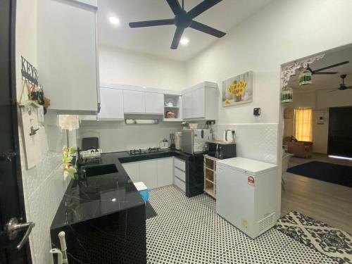 a kitchen with white cabinets and a black counter top at Maison Helysa Homestay in Lumut
