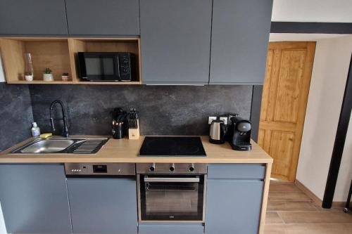 une cuisine avec un évier et une cuisinière four supérieur dans l'établissement Le Petit Colin 1er, à Pontarlier