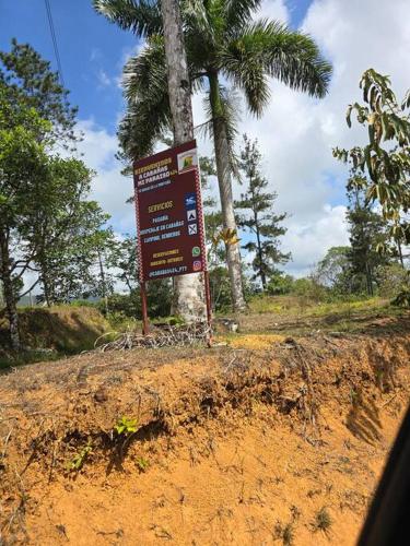 a sign next to a palm tree on a dirt road at Cabaña paradisíaca en Cerro Azul in Los Bravos