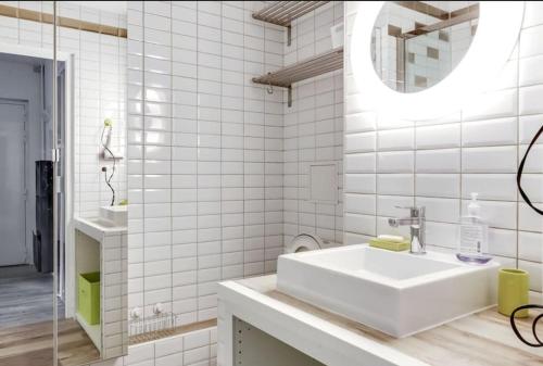 une salle de bain blanche avec un lavabo et un miroir dans l'établissement Studio Avec vue Panoramique Paris 11, à Paris