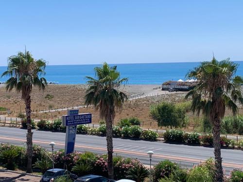 a road with palm trees next to a beach at Hotel San Gaetano in Grisolia
