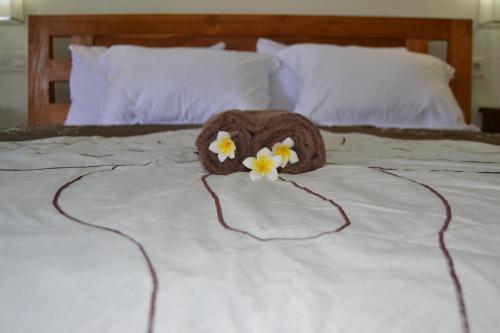 a brown stuffed animal with flowers on a bed at Pujihouse One in Legian