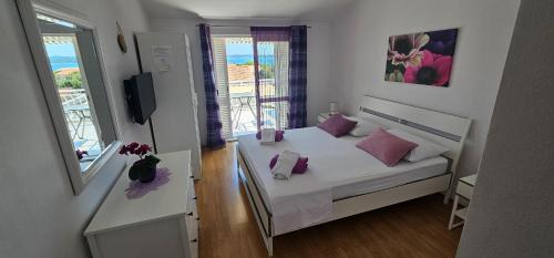 a small bedroom with a white bed with purple pillows at Apartmani Pavla in Orebić
