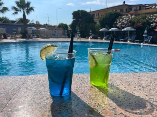 two drinks sitting on a table next to a swimming pool at Hotel San Gaetano in Grisolia