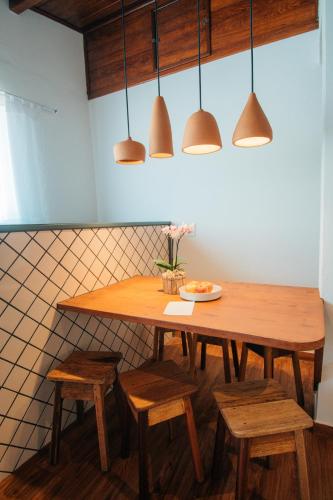 a kitchen with a wooden table with chairs and pendant lights at Pousada Girassol Morro de São Paulo in Morro de São Paulo