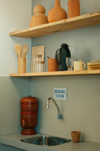 a kitchen with a sink and shelves with pottery at Pousada Girassol Morro de São Paulo in Morro de São Paulo