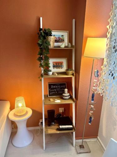 Una pequeña habitación con un estante con una mesa y una lámpara. en Spacieux studio Arcachon centre 5 Nights min, en Arcachon