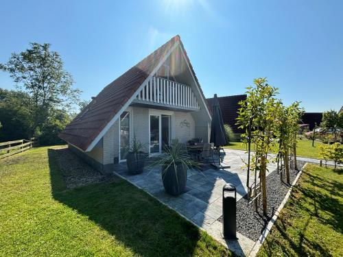 a small white house with a pitched roof at Haus Kormoran am Lauwersmeer 175 in Anjum