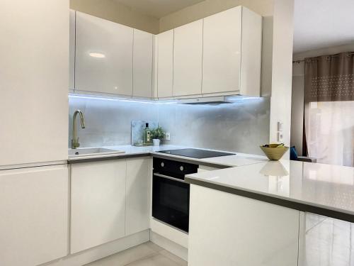 une cuisine avec des armoires blanches et un lave-vaisselle noir dans l'établissement Modern flat Cannes Center, à Cannes