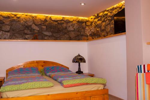 a bed in a bedroom with a stone wall at Къща за гости Ози in Ovchartsi