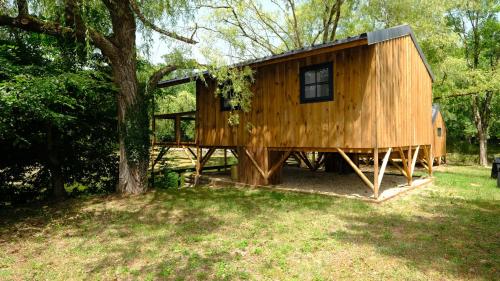 a large wooden house in a field with a tree at Les Cabanes de Lara in Ménesplet
