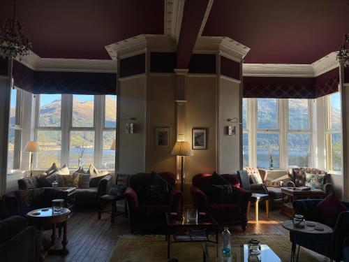 a living room with couches and tables and windows at Creag Mhor Lodge in Onich
