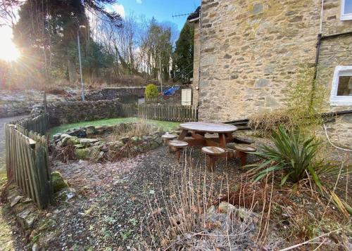 a picnic table in front of a stone building at Loch Lomond 2 Bedroom Apartment in Tarbet