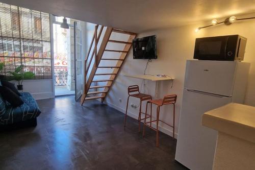 una cucina con frigorifero e 2 sgabelli in una camera di Studio L'Occitan en plein centre ville avec balcon a Lézignan-Corbières