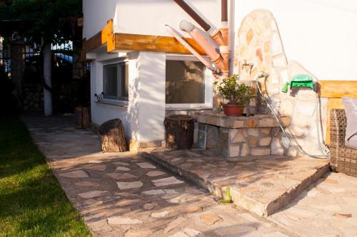 a patio with a stone fireplace next to a house at Къща за гости Ози in Ovchartsi