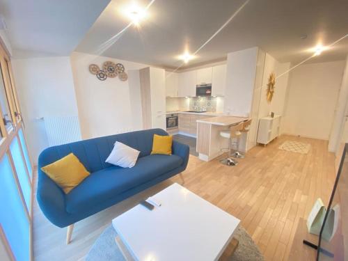 un salon avec un canapé bleu et une cuisine dans l'établissement Appartement haut standing Paris La Defense Arena, à Nanterre