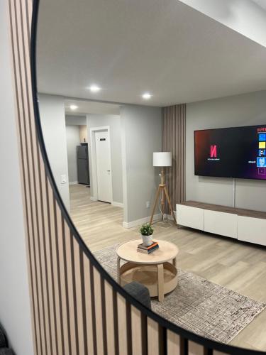 a living room with a staircase with a television and a table at The Old Trafford - Stylish 2 bed suite in Calgary