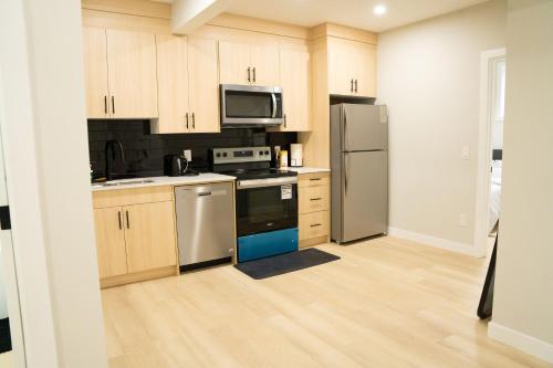 a kitchen with stainless steel appliances and wooden cabinets at The Old Trafford - Stylish 2 bed suite in Calgary