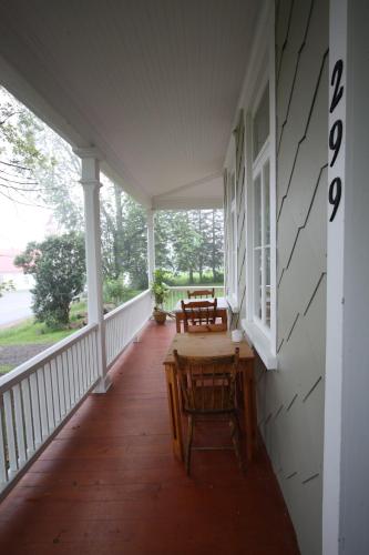 a porch with a table and two benches on it at Auberge Carpe Diem in Baie-Saint-Paul