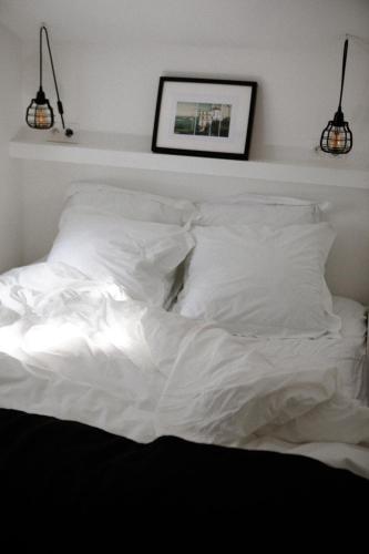an unmade bed with white sheets and pillows at VILLA Centre Guethary piscine acces ocean a pied in Guéthary