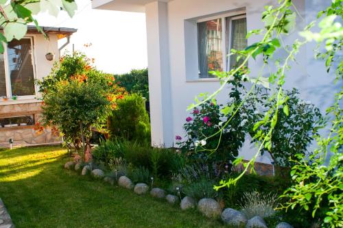 a garden with flowers and plants in front of a house at Къща за гости Ози in Ovchartsi