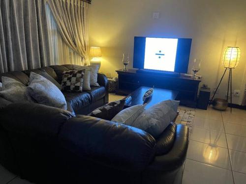 プレトリアにあるTG Villa Menlynのソファと薄型テレビのあるリビングルーム