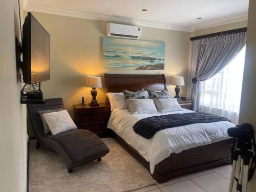 プレトリアにあるTG Villa Menlynの大きなベッドと椅子のある寝室